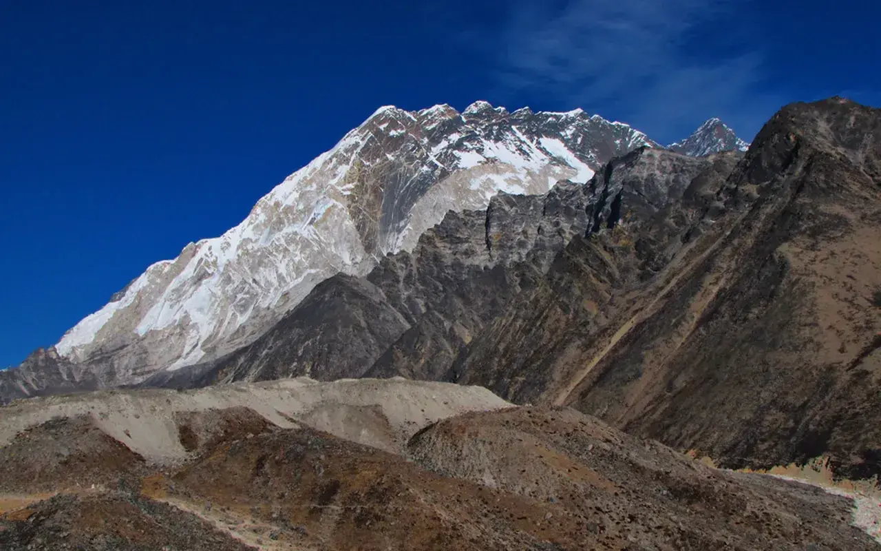 Majestatyczny Mount Everest w śnieżnej koronie, widok z bazy pod Everestem. Surowe, skaliste zbocza i błękitne niebo.