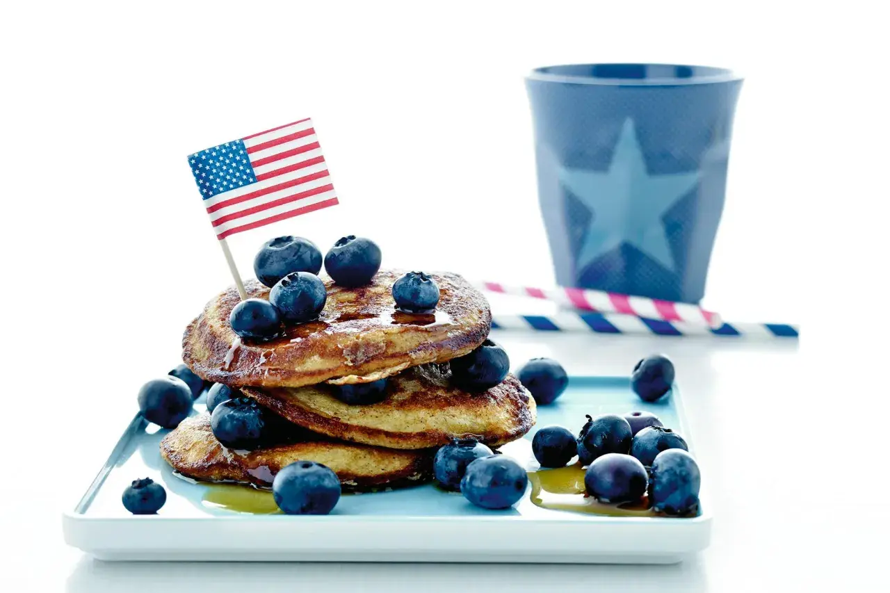 En stapel pannkakor med blåbär och en amerikansk flagga. Perfekt för att frysa pannkakor och njuta av en amerikansk frukost.