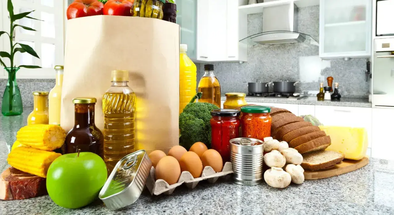Un sacco di carta pieno di pomodori, uova, pane, formaggio e altri cibi proteici, pronti per essere cucinati.
