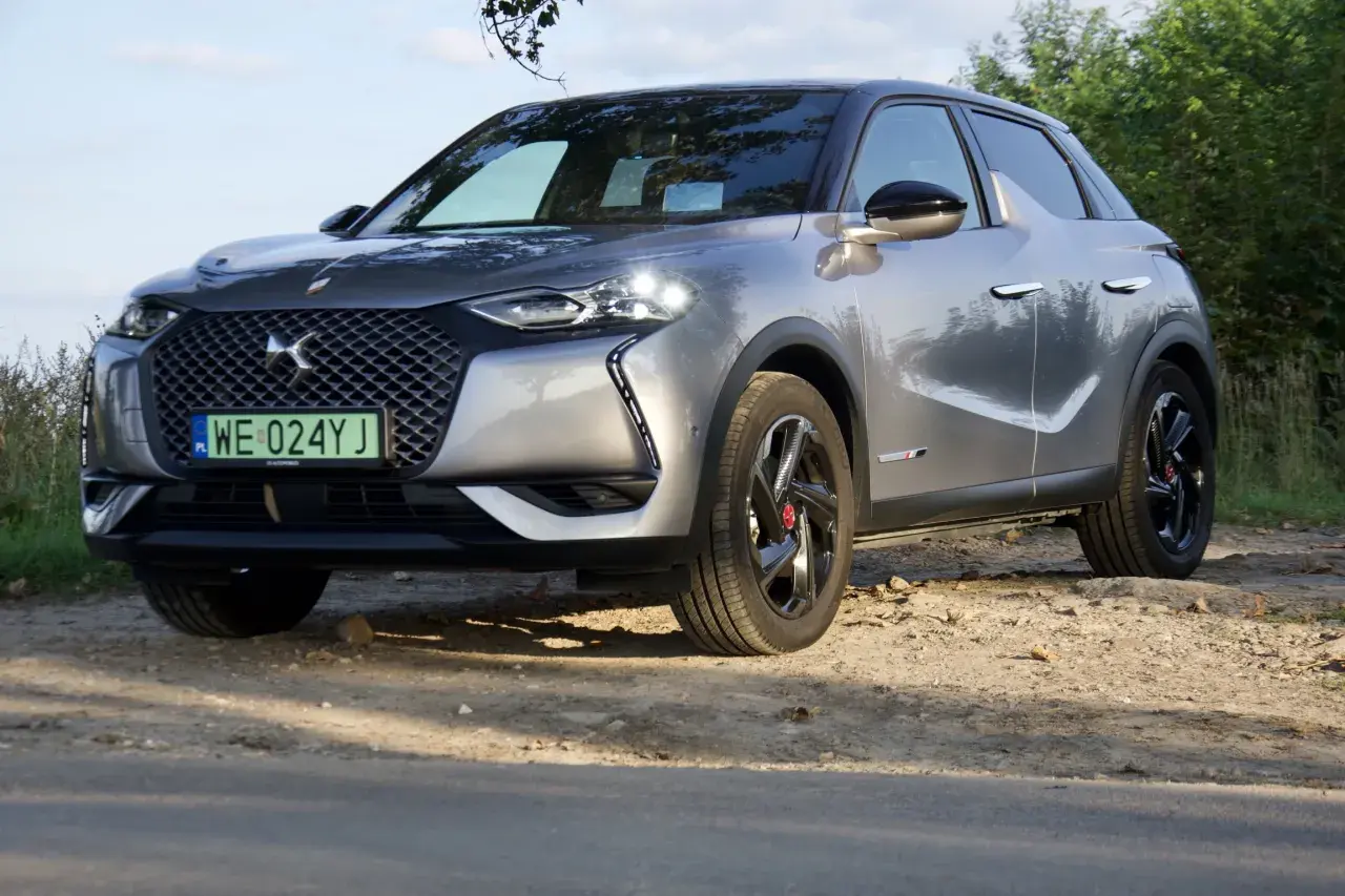 Elegancki, srebrny ds3 crossback na tle zieleni.
