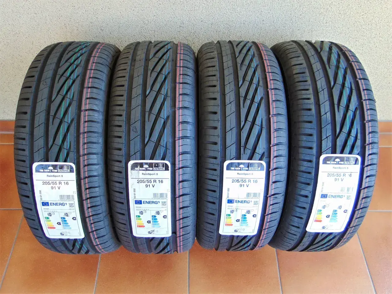 Cztery nowe opony Uniroyal RainSport 5 o rozmiarach 205/55 R 16 91V, z etykietami energetycznymi.