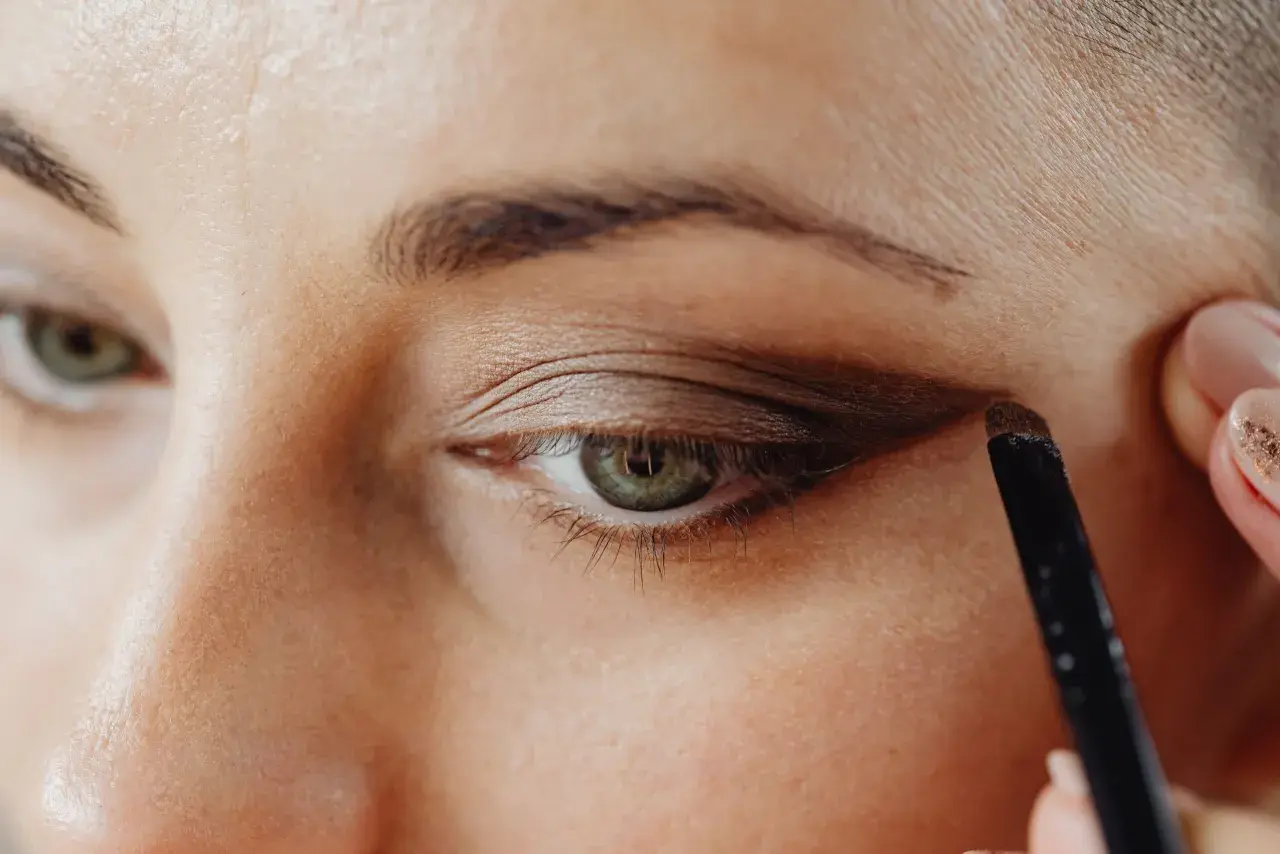 Application d'un fard brun pour comment maquiller des yeux verts. Un pinceau est utilisé pour définir la paupière.