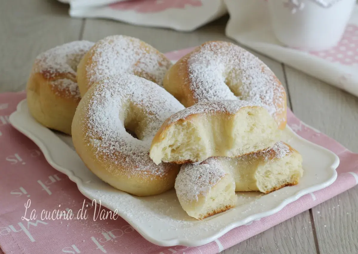 Ciambelle al forno soffici e profumate, cosparse di zucchero a velo. Una delizia per la colazione o la merenda.
