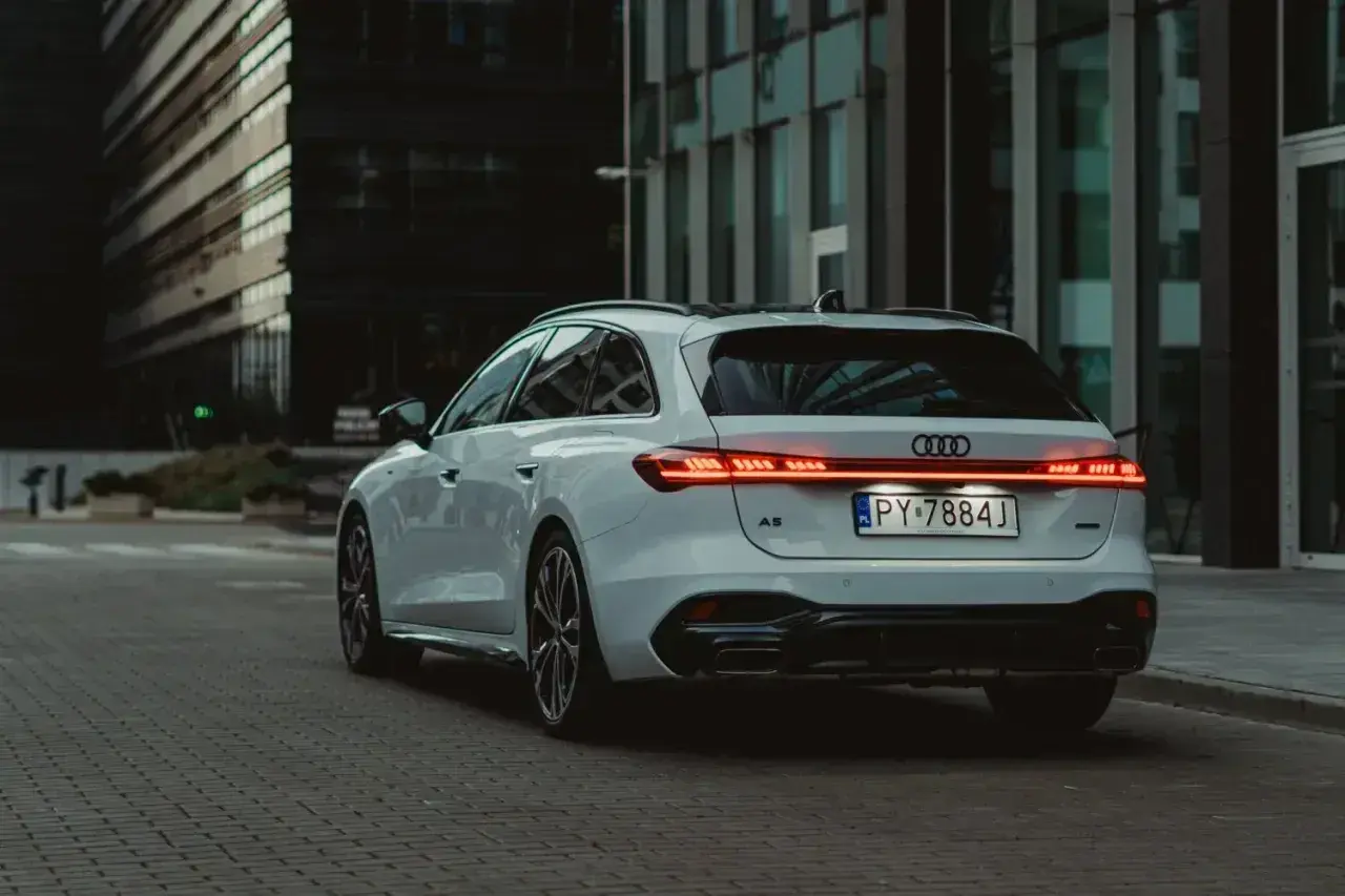 Białe Audi A5 Avant 2025 z nowoczesnymi światłami LED na tle miejskiej architektury.