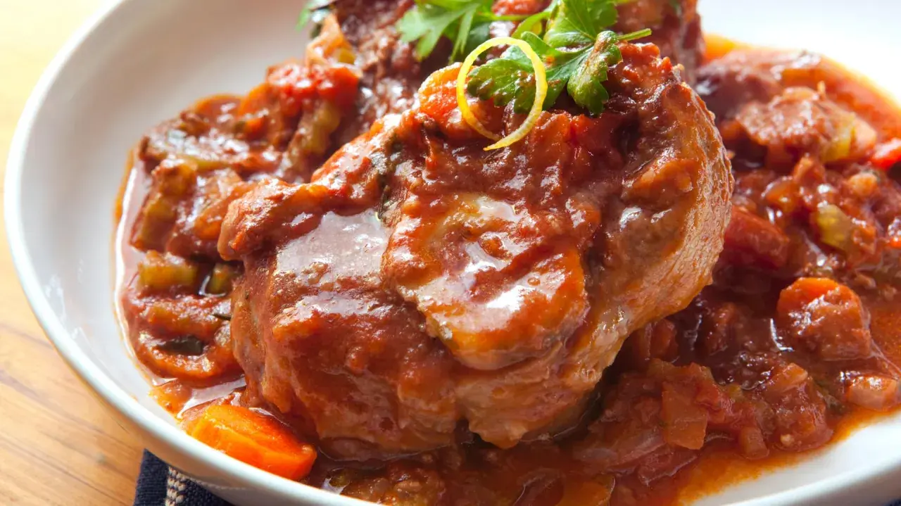 Herzhaftes Ossobuco Rezept in Tomatensoße mit Karotten und Petersilie, serviert in einer weißen Schüssel.