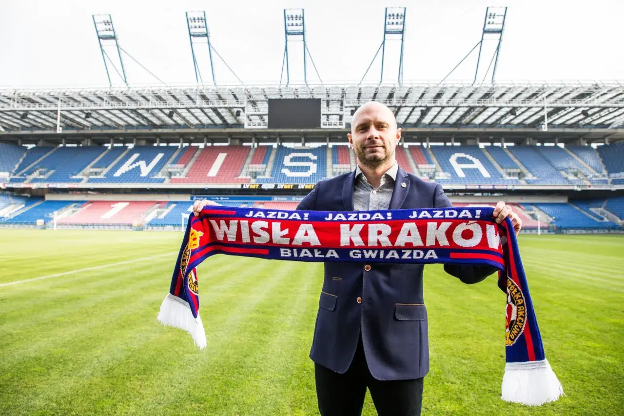 Artur Skowronek z szalikiem Wisły Kraków na tle stadionu. "Jazda! Wisła Kraków! Biała Gwiazda!" - krzyczy kibic.
