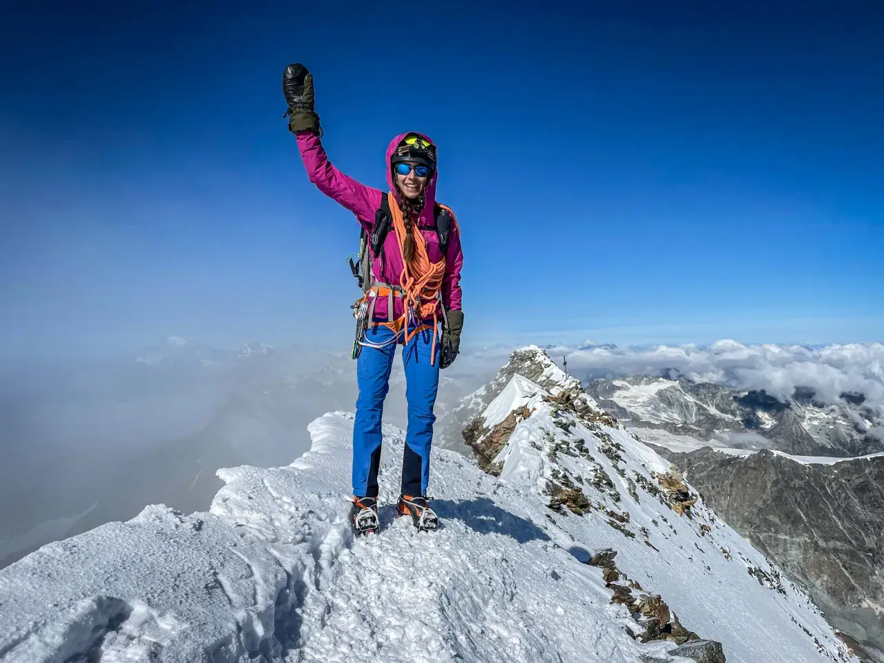 Erfolgreiche Bergsteigerin jubelt auf dem schneebedeckten Matterhorn Gipfel.