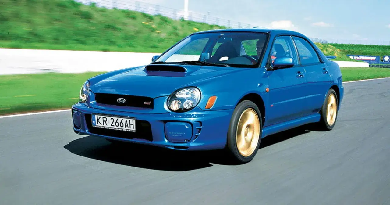 Niebieskie, małe szybkie auto Subaru Impreza WRX STI pędzi po torze wyścigowym.