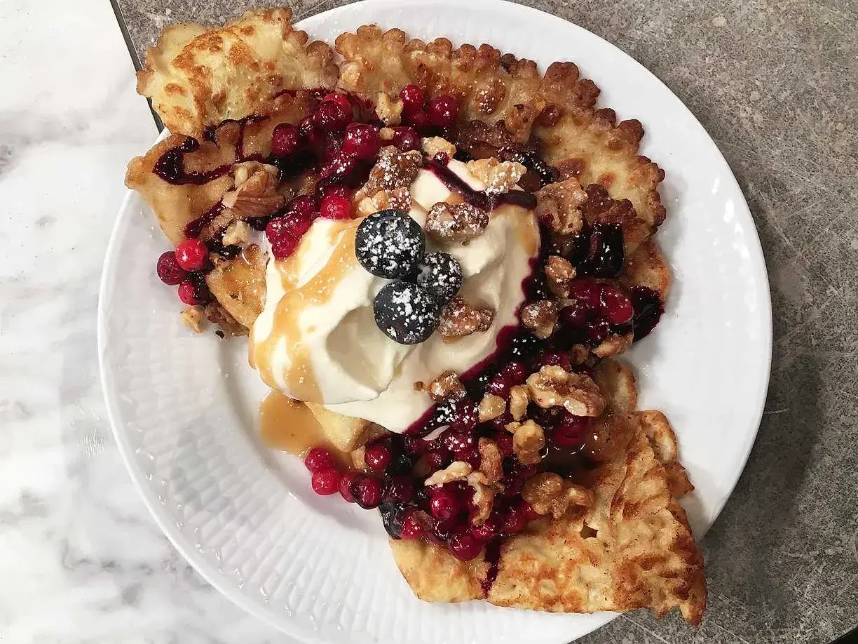 En härlig funnel cake toppad med vispgrädde, bär, nötter och sirap. En dröm för alla sötsugna!