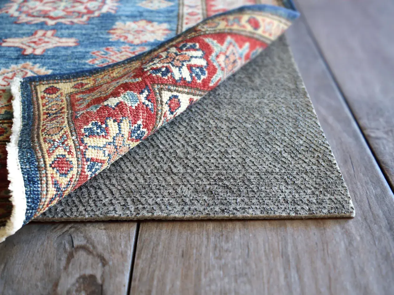 A rug is flipped to reveal its backing, showing how to waterproof a rug with a protective layer.