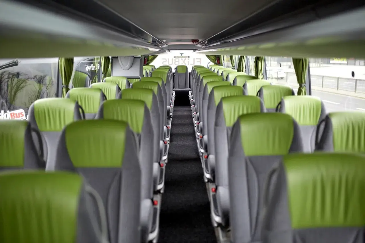 Wnętrze autokaru FlixBus, zielone siedzenia tworzą pusty korytarz. Idealne miejsce na podróż.