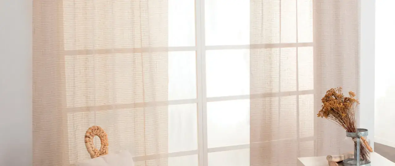 Tende leggere color crema coprono una finestra con divisori bianchi. L'altezza del bastone tende dal soffitto è ottimale per un look arioso.