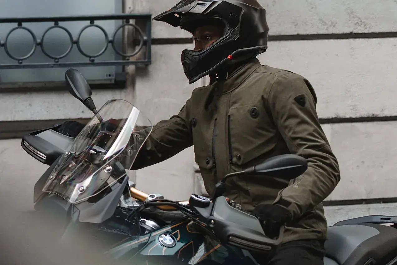 Motociclista con casco y chaqueta de aventura, que es Gore-Tex, lista para el viaje.
