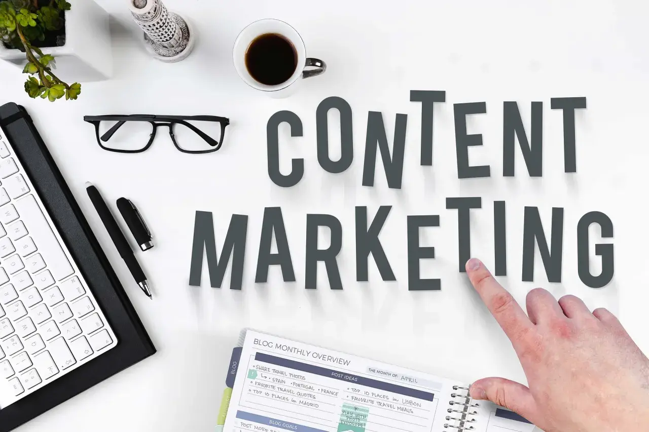 Content SEO Manager do czego służy? Planowanie i tworzenie treści, by przyciągnąć odbiorców. Na biurku klawiatura, okulary, kawa i notatnik.