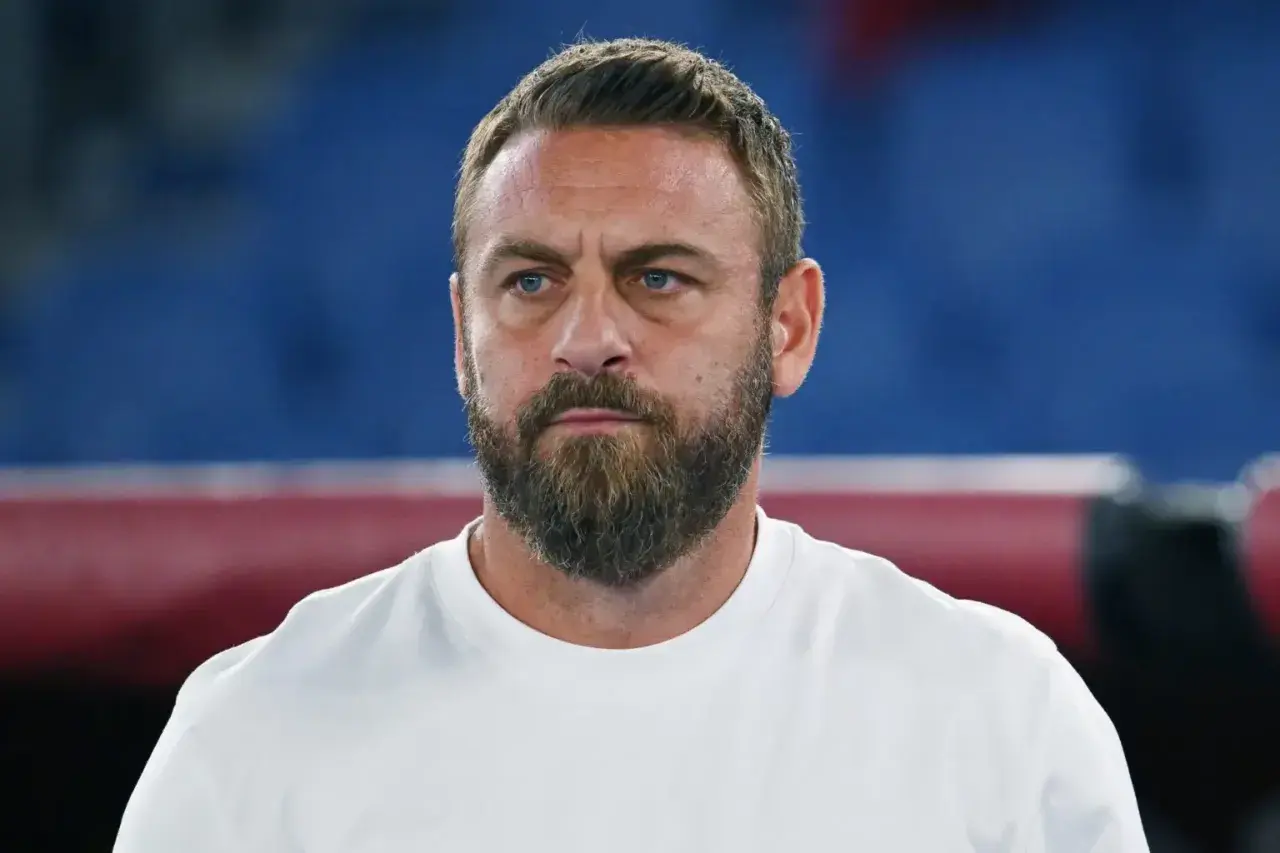 Close-up of a man with a beard and blue eyes wearing a white t-shirt.