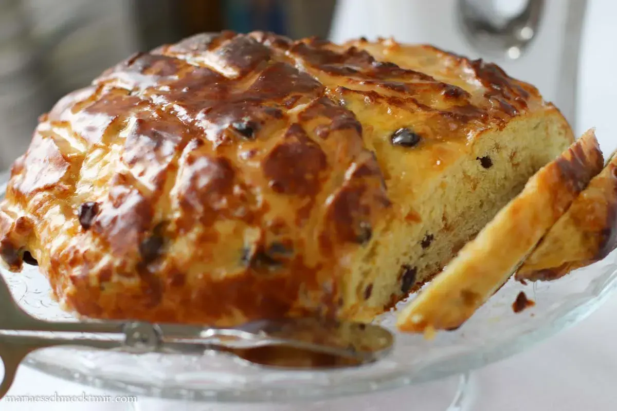 Ein goldbraun gebackenes Osterbrot mit Rosinen, glasiert und angeschnitten, bereit zum Genießen.