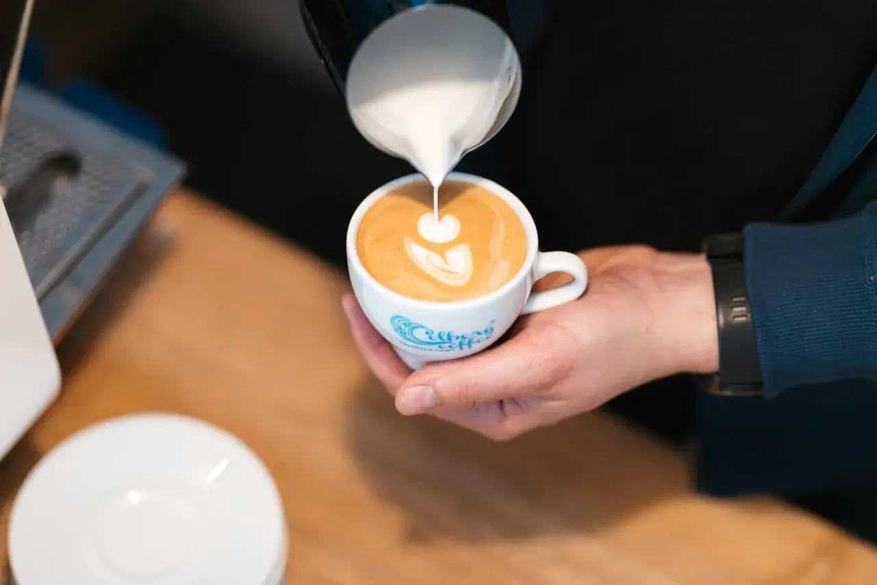 Barista tworzy latte art na podwójnym espresso z mlekiem.