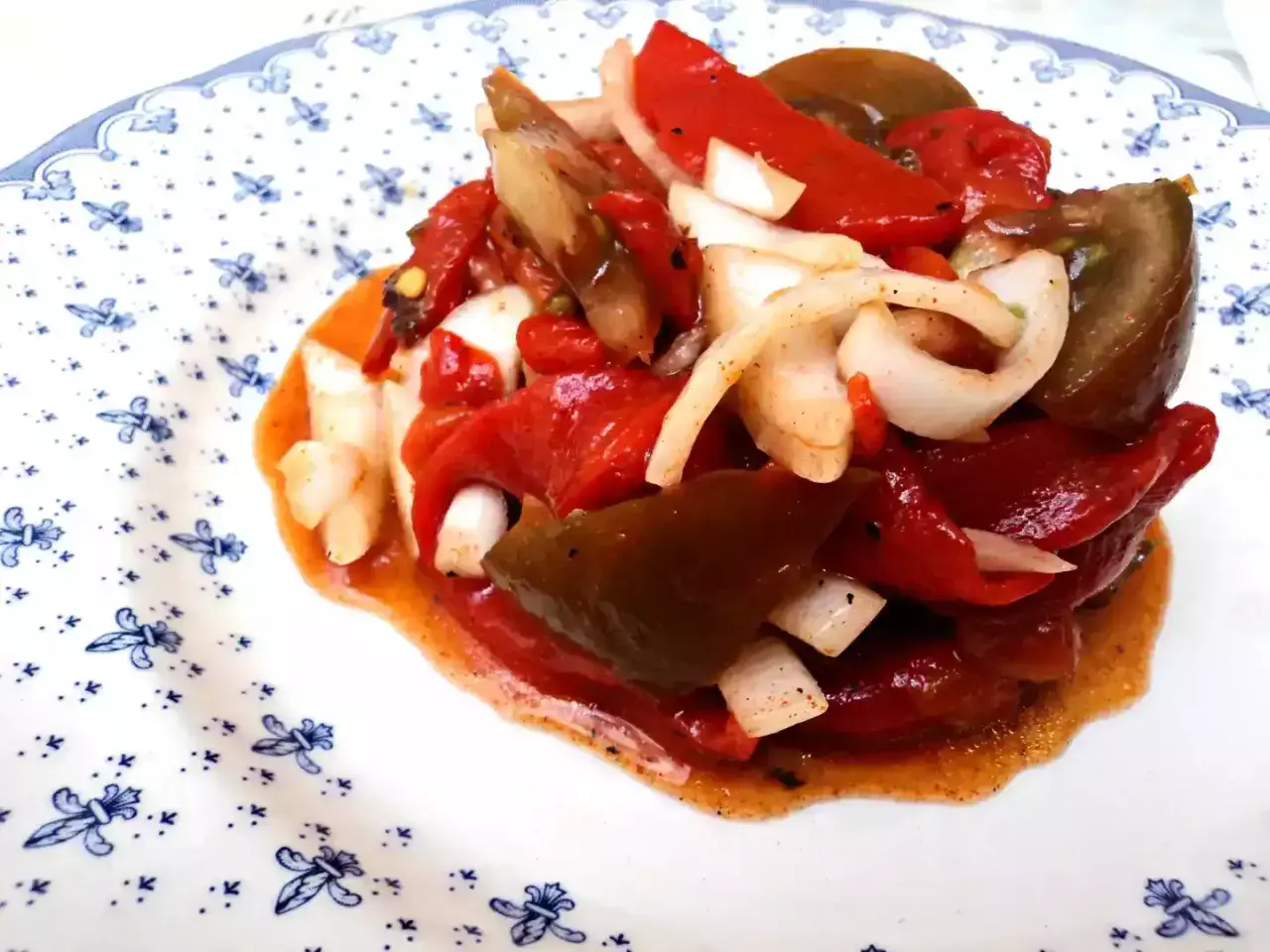 Deliciosa ensalada de pimientos asados con cebolla, bañada en un aderezo rojizo. Un plato lleno de sabor y color.