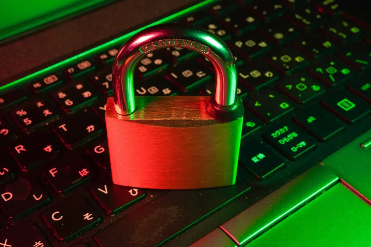 Un cadenas sur un clavier d'ordinateur, symbolisant la **sécurité informatique**. La lumière rouge et verte crée une ambiance de protection numérique.