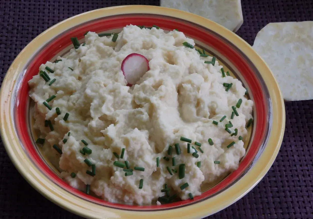 Puszyste puree z selera, udekorowane szczypiorkiem i plasterkiem rzodkiewki, prezentuje się apetycznie.