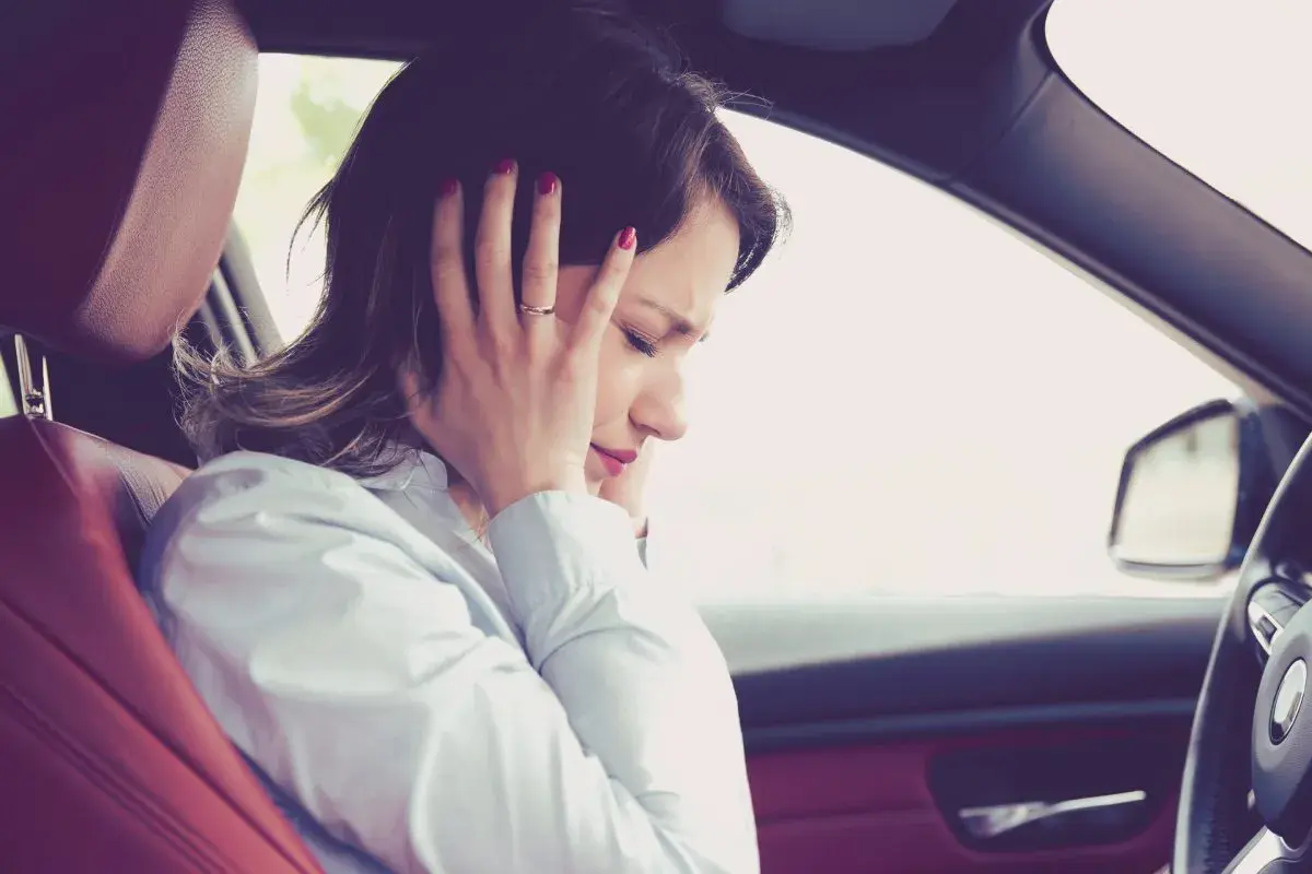 Donna in auto si tappa le orecchie per il fastidioso cigolio macchina.