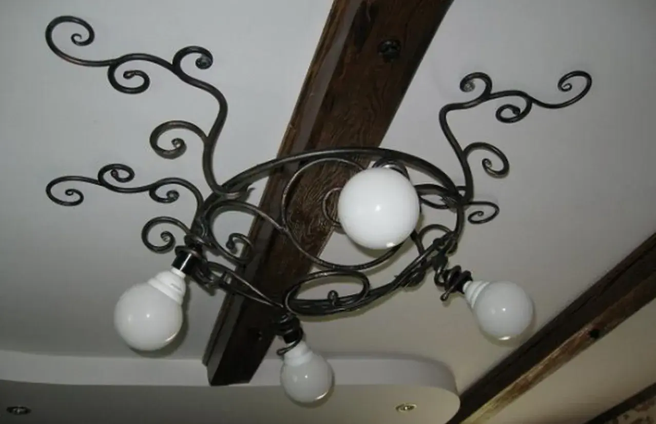 Elegantes lámparas de forja de techo con volutas y globos de cristal blanco, adornando un techo con vigas de madera.