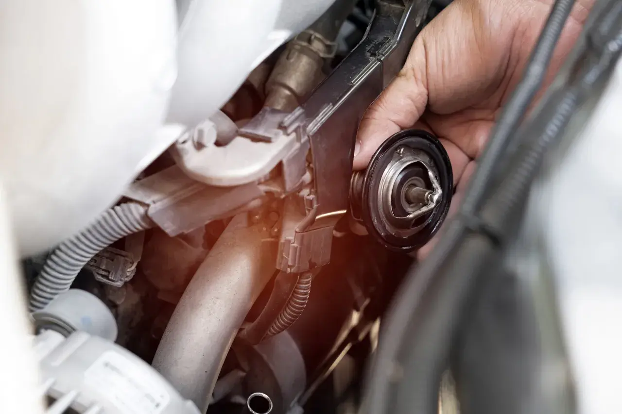 Mano che rimuove la valvola termostatica, forse perché non chiude bene e causa problemi al motore.