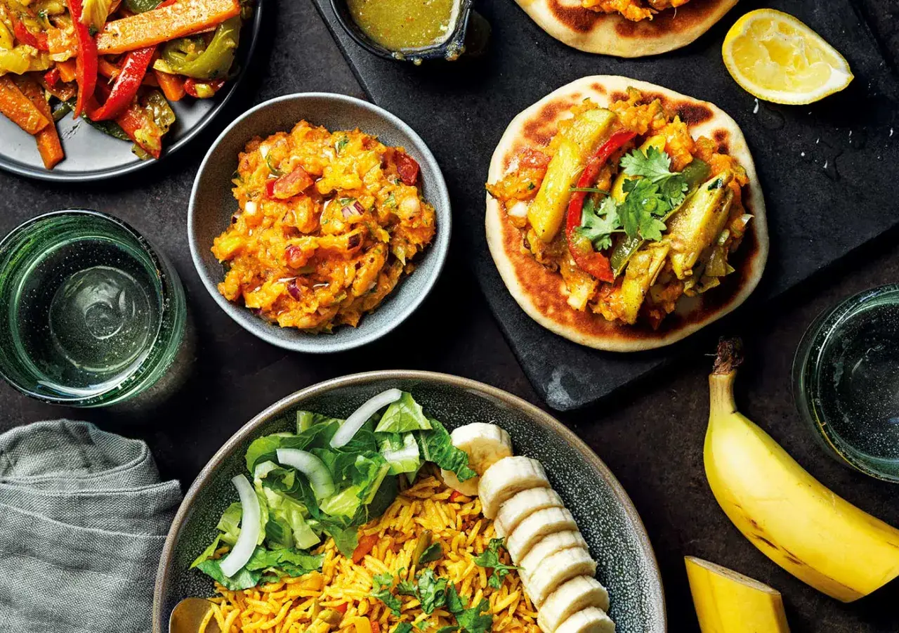 En härlig måltid med somalisk mat: ris, sallad, grönsaksröra och små bröd med fyllning. En banan och en citronklyfta fulländar bilden.