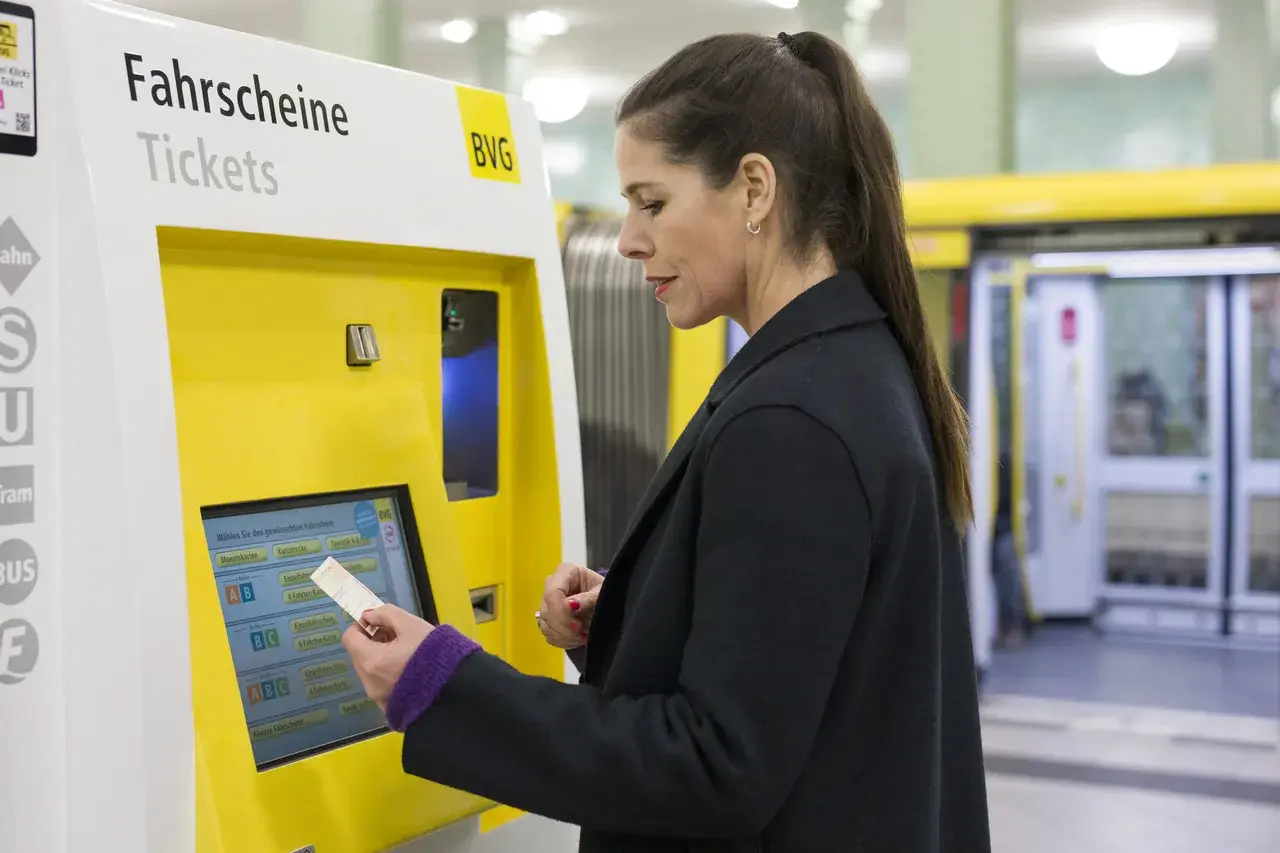 Frau kauft am Automaten ein Ticket. Die Bedeutung von SPNV (Schienenpersonennahverkehr) wird hier durch den Kauf eines Fahrscheins für die Fahrt mit Bus oder Bahn deutlich.