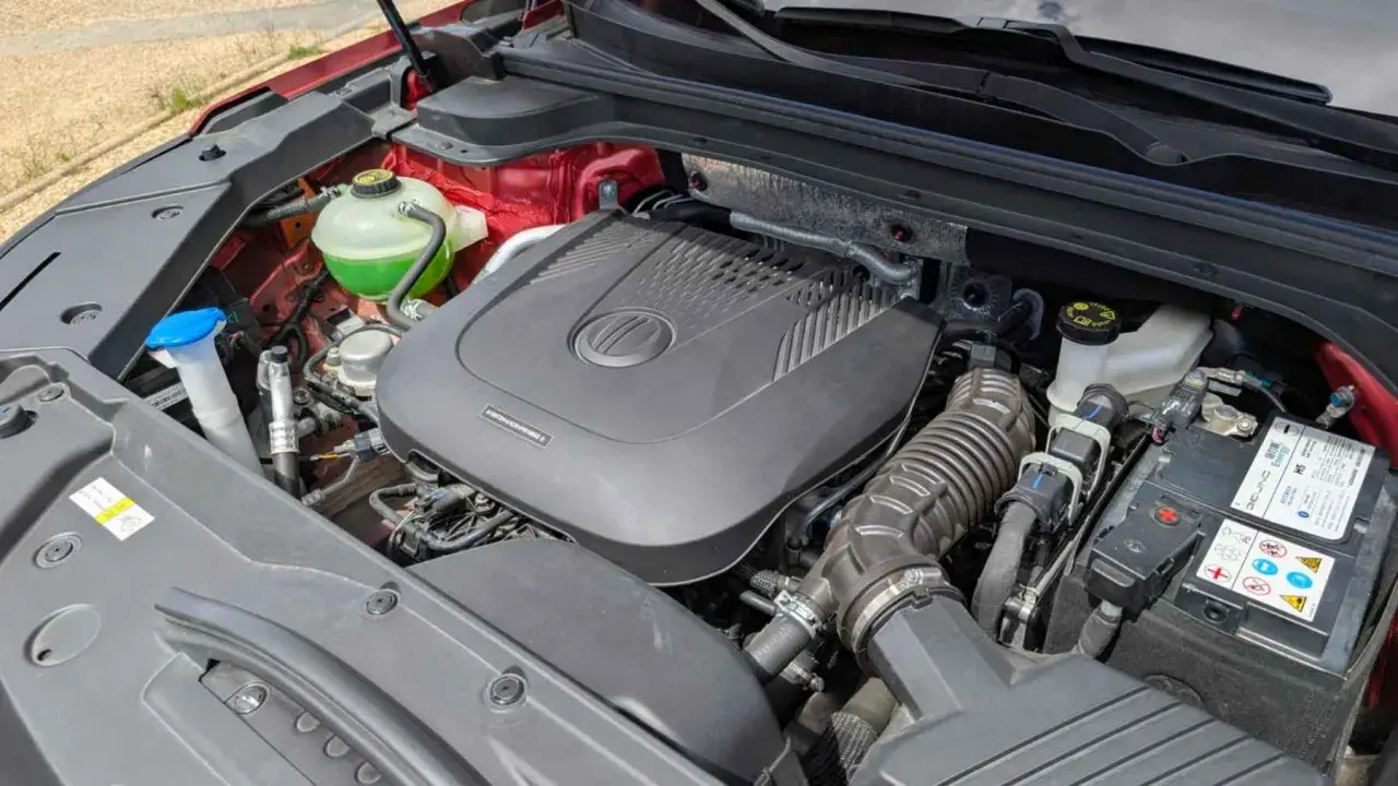 Motor de coche con cubierta negra, batería y depósito de refrigerante verde. ¿Cuántos caballos tiene un coche normal?