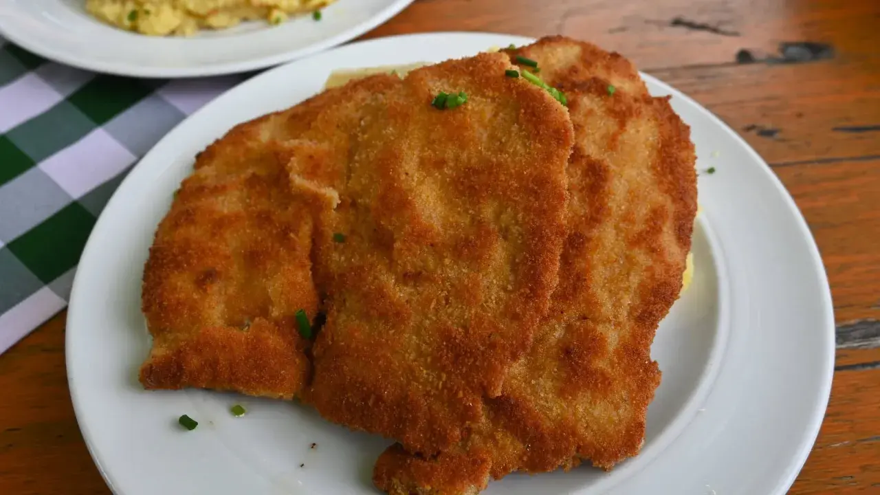 Zwei goldbraune Schnitzel auf einem Teller, garniert mit Schnittlauch. Ein Klassiker der Berliner Küche, der Appetit macht.