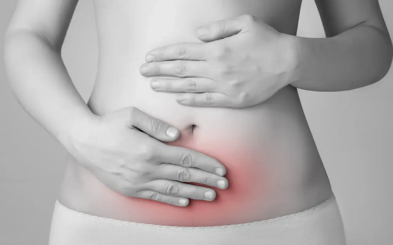 Mani sul ventre con area rossa che indica dolore. L'endometriosi può causare invalidità e sofferenza cronica.