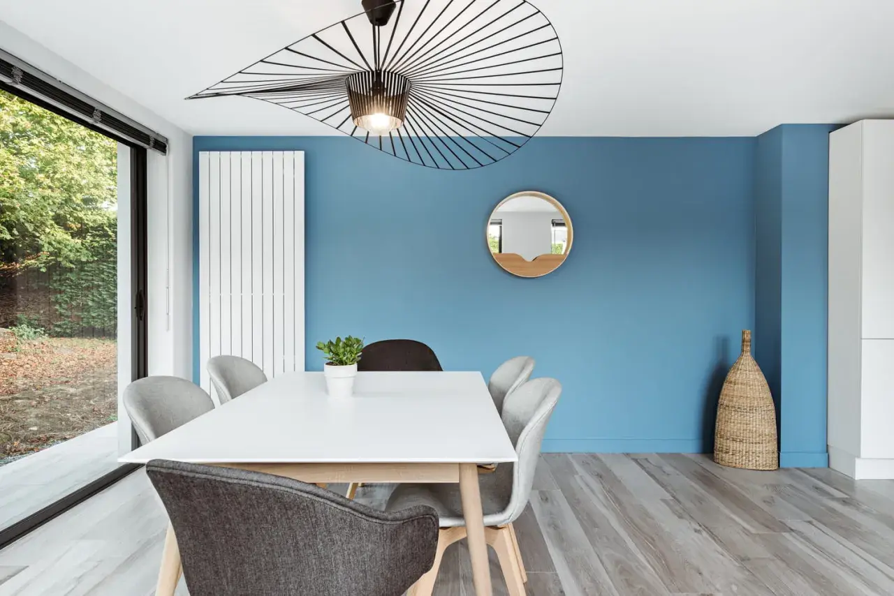 Un mur bleu vif illumine cette salle à manger moderne. Quel mur peindre en couleur ? Celui-ci, sans hésiter !