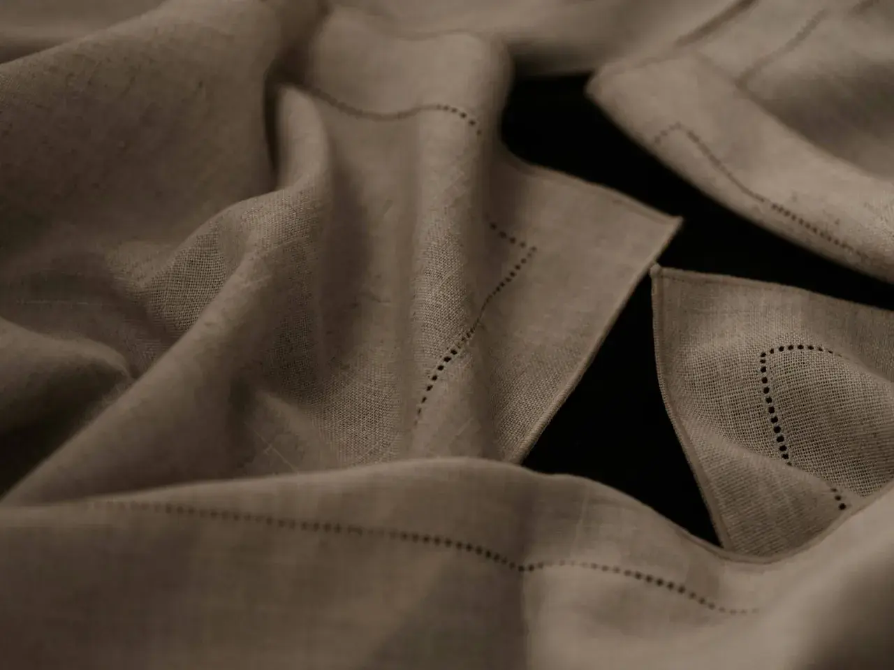 Draped linen fabric, perfect for breathable summer pants, features delicate dotted stitching along its edges.