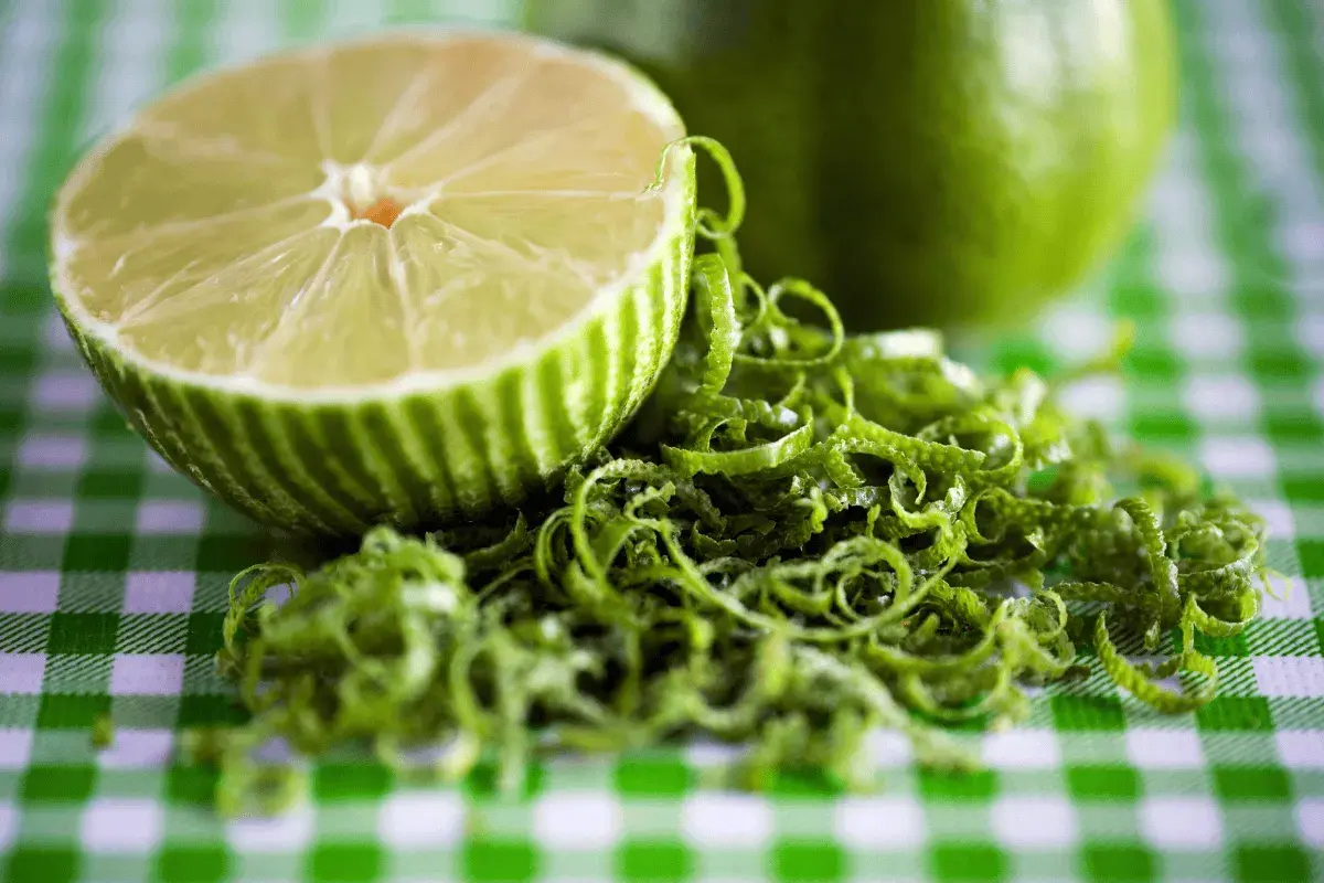 Połówka limonki i jej skórka na zielono-białej kratce. Czy limonka jest zdrowa? Tak, to cytrus pełen witamin!