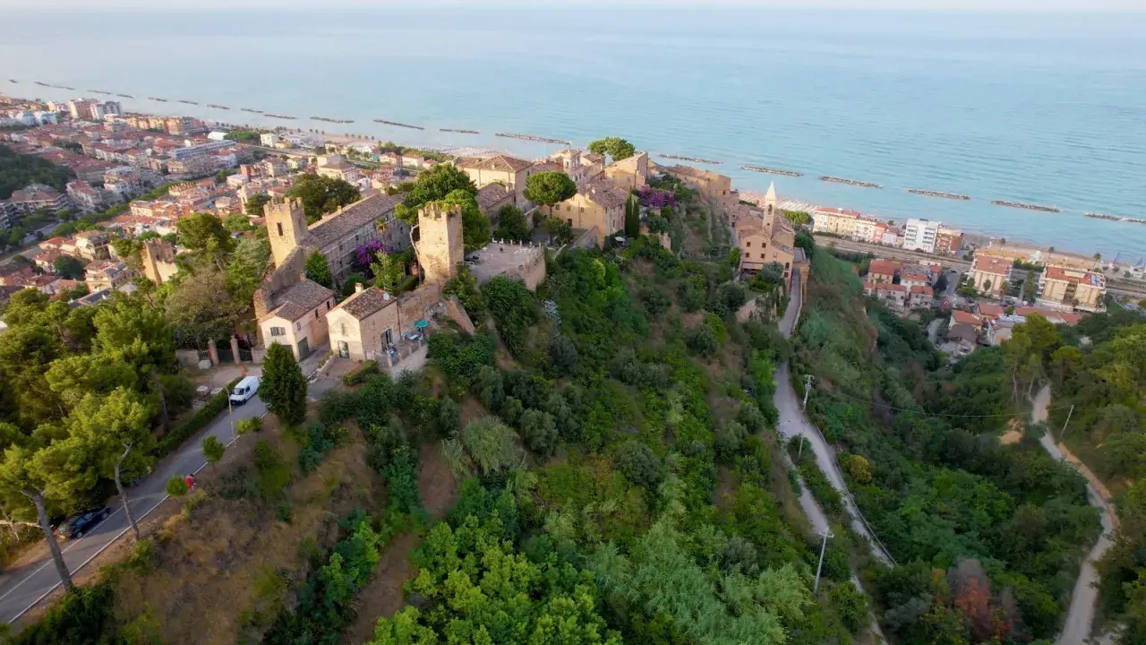Borgo medievale su una collina affacciata sul mare Adriatico, con il lungomare di Cupra Marittima in lontananza.
