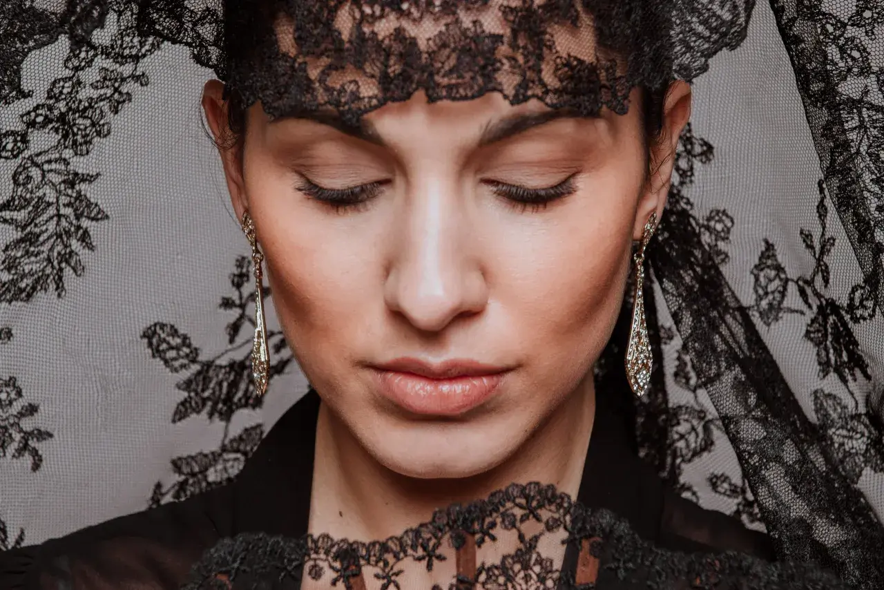 Mujer con peinados de mantilla, luciendo pendientes largos y un abanico de encaje.