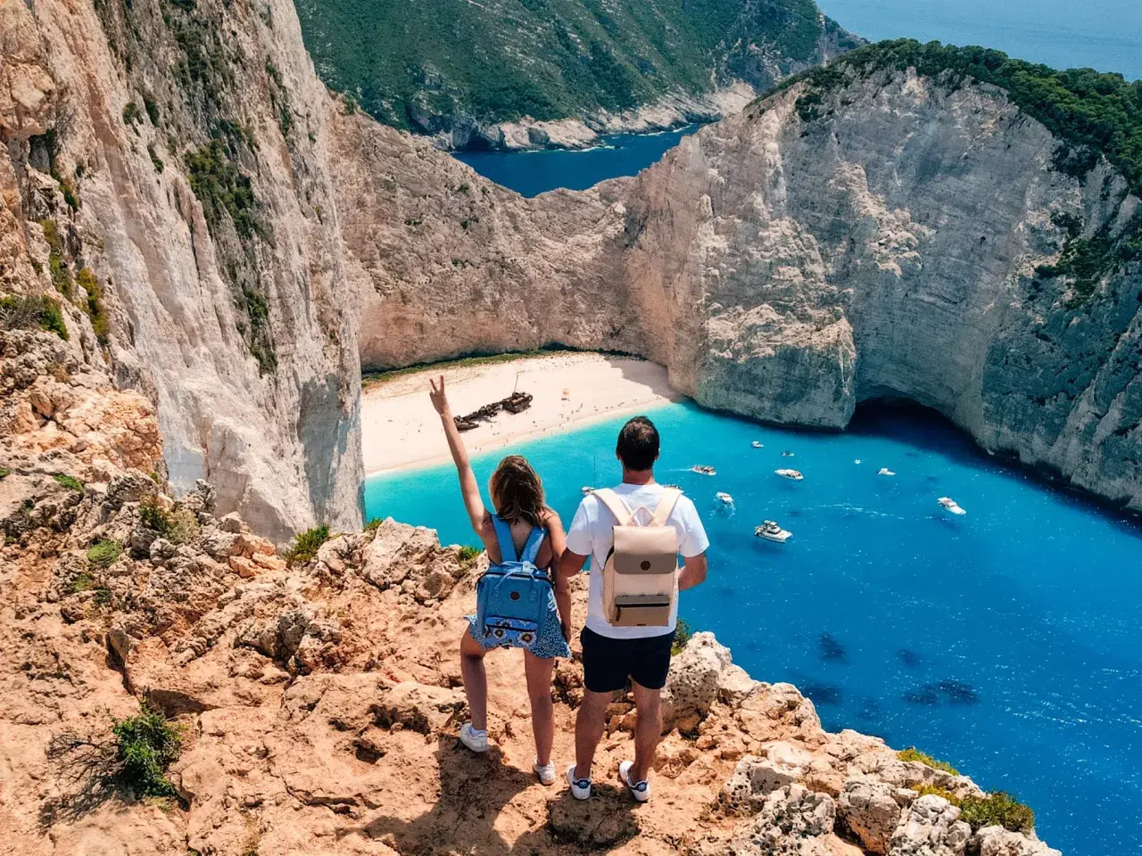 Couple admirant la baie de Navagio, une des plus belles plages des top 5 des îles grecques. L'eau turquoise et les falaises blanches sont spectaculaires.