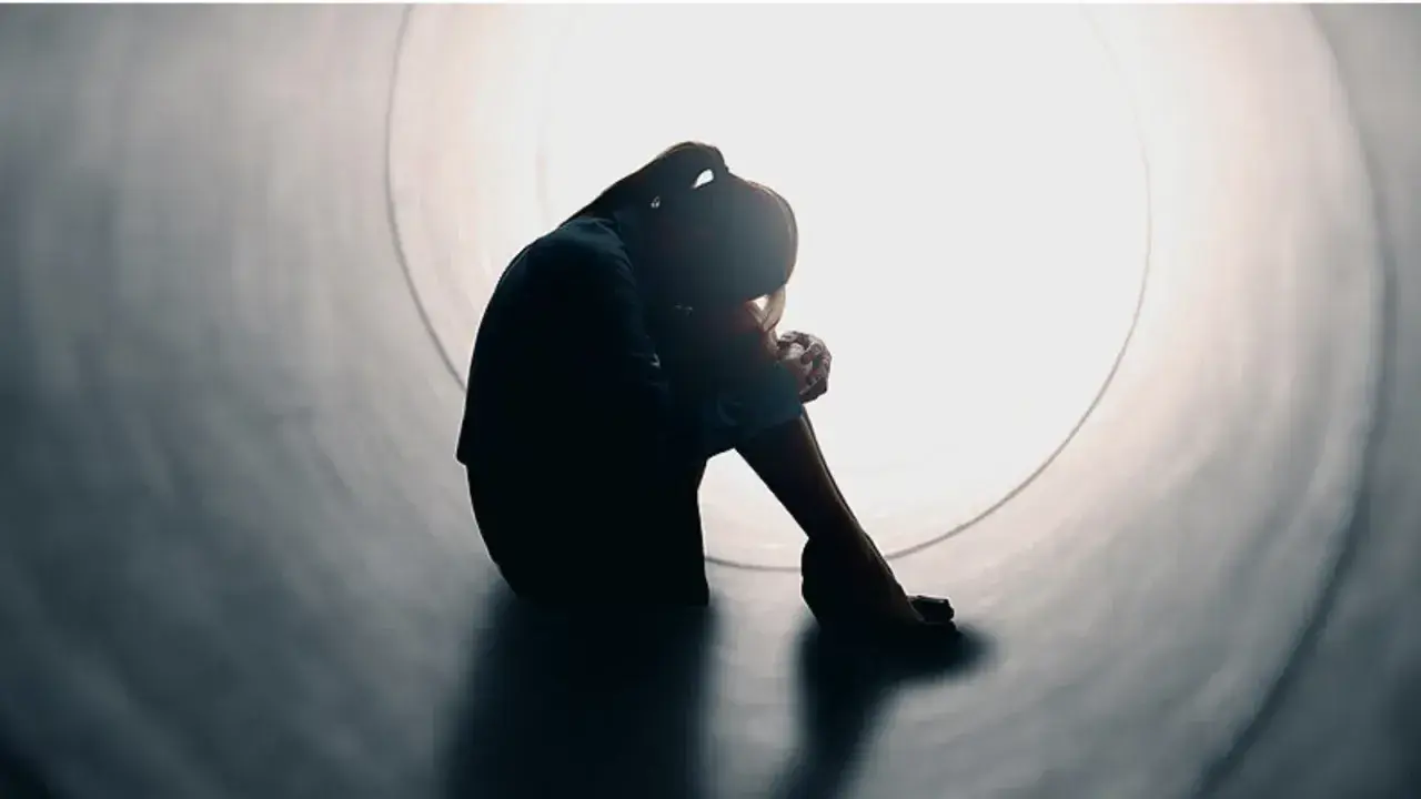Silhouette di una persona rannicchiata in un tunnel, simbolo di solitudine e mancanza di affetto.