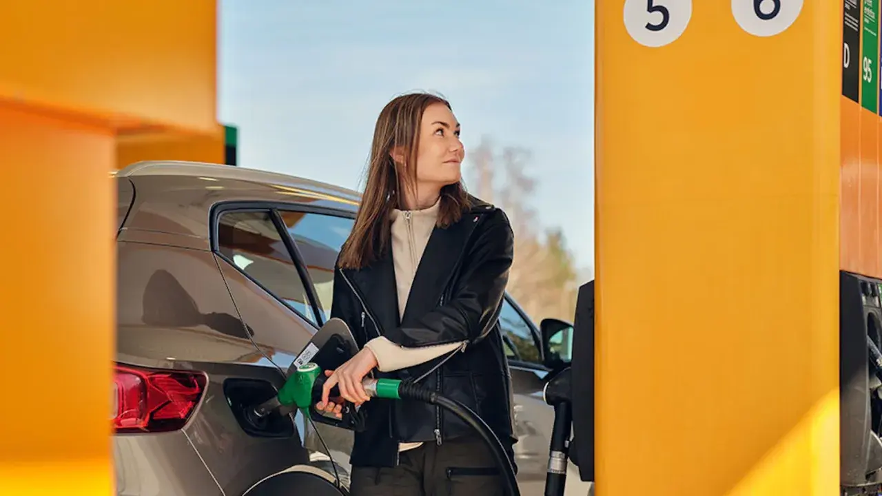 Kvinna tankar sin bil med hvo diesel vid en gul pump.