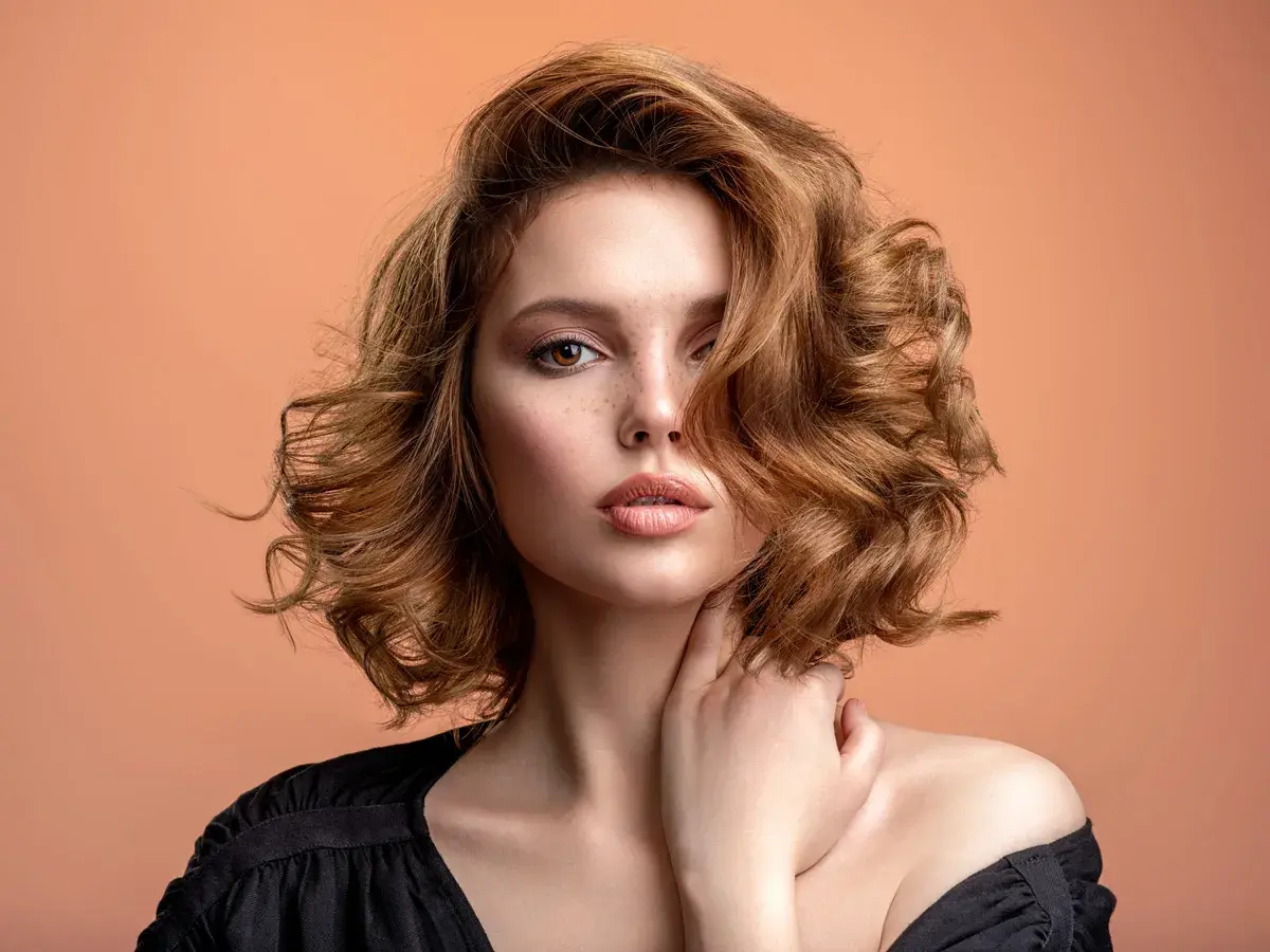 Mujer con pelo ondulado color cobre, un estilo que marca la tendencia pelo 2026.
