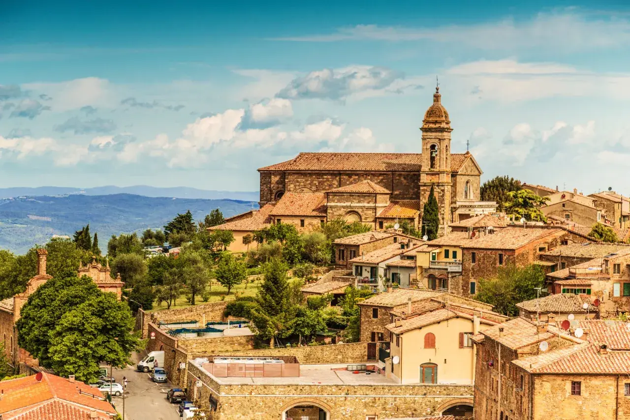 Panoramica di Montalcino, borgo medievale toscano con la sua imponente cattedrale e le case in pietra, immerso nel verde delle colline.