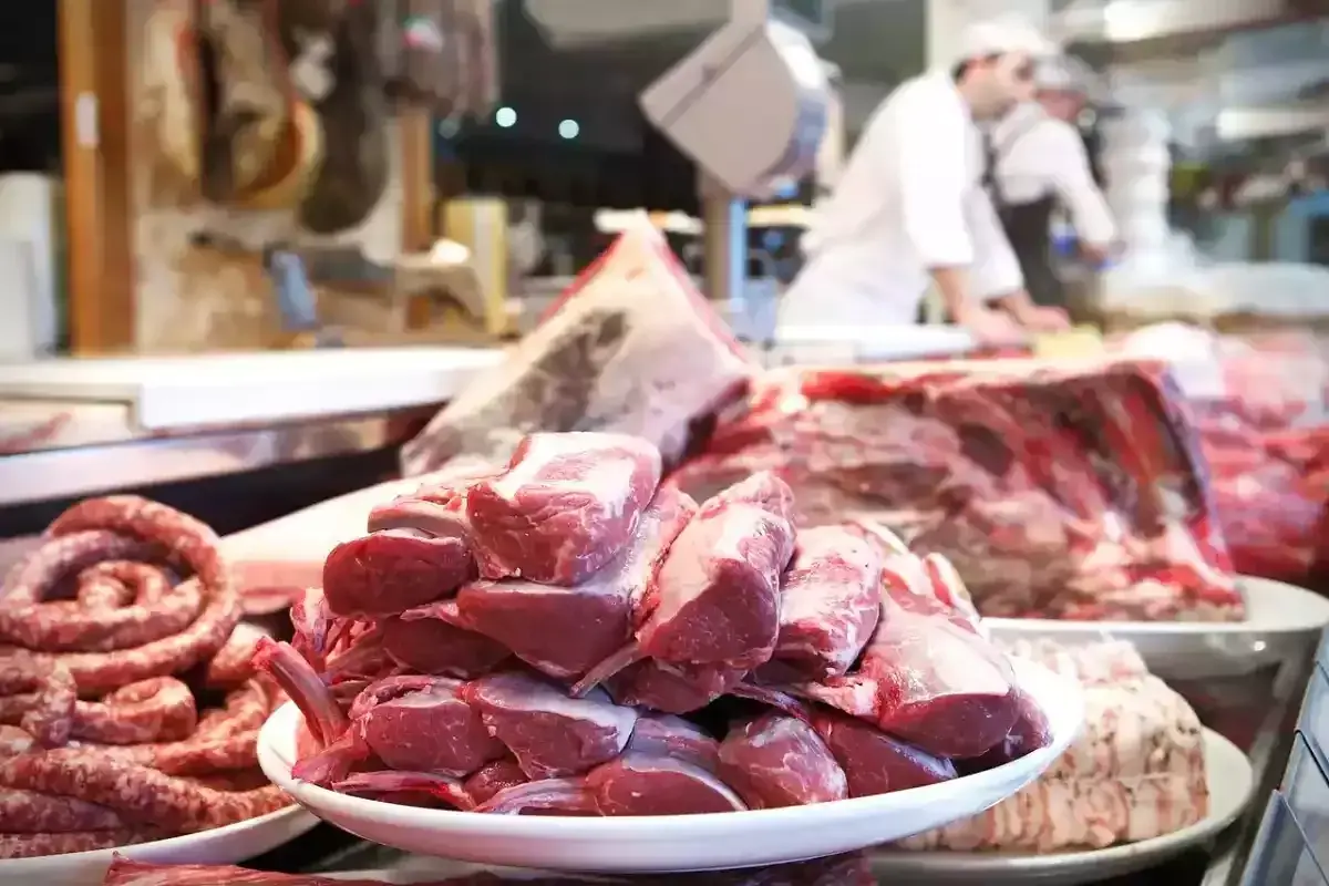 Carnes grasas y magras en un puesto de carnicería. Salchichas en espiral y chuletas de cordero apiladas en platos.
