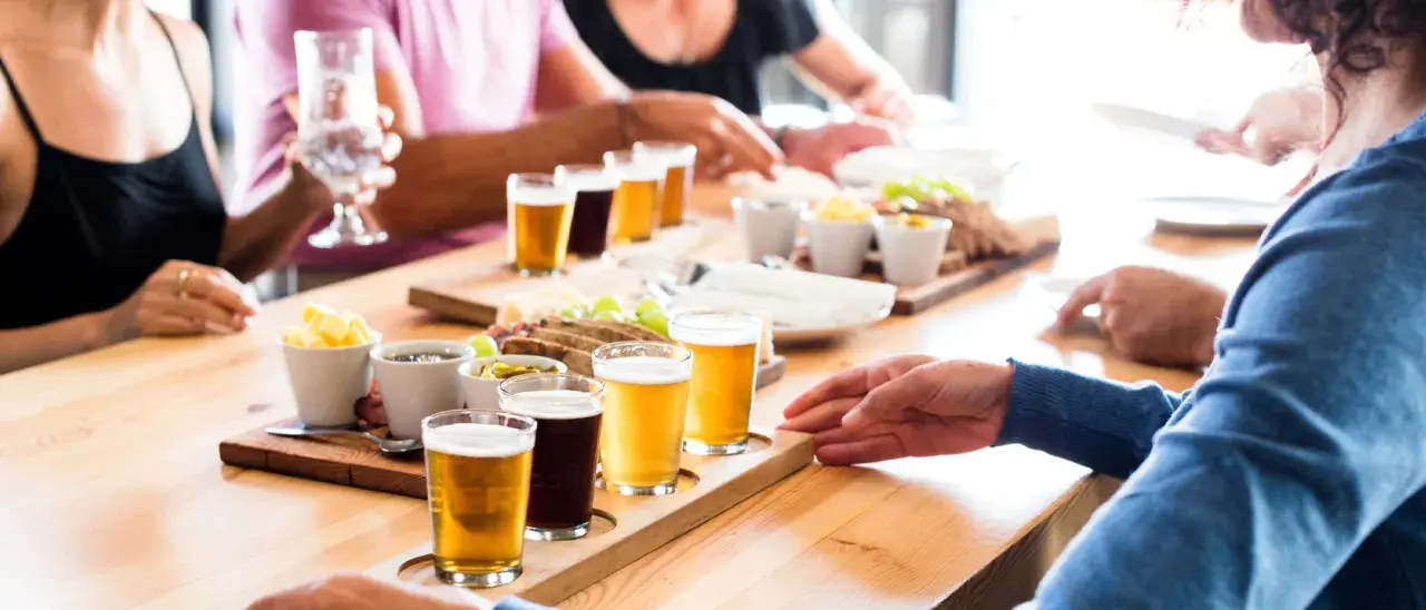 Un gruppo di persone partecipa a un corso degustazione birra, assaggiando diverse varietà accompagnate da stuzzichini.