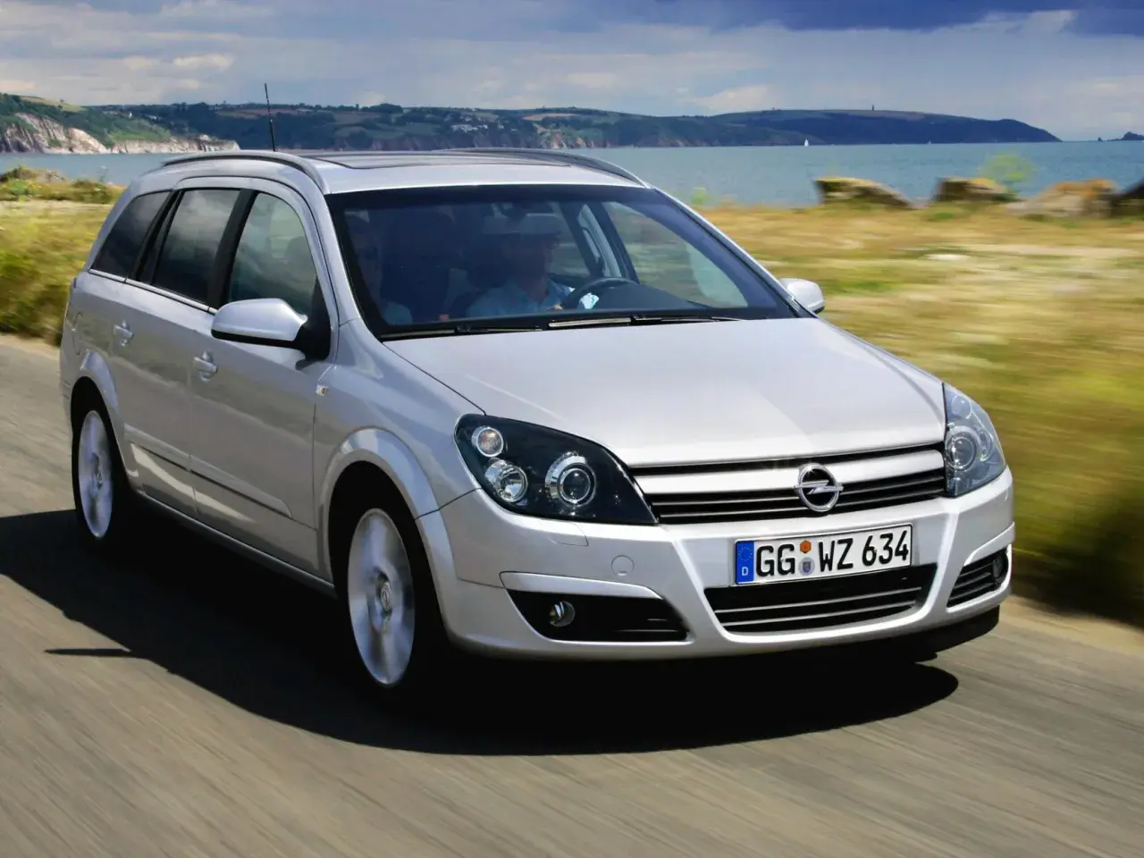 Srebrne kombi Astra H 1.7 CDTI jedzie wzdłuż malowniczego wybrzeża.