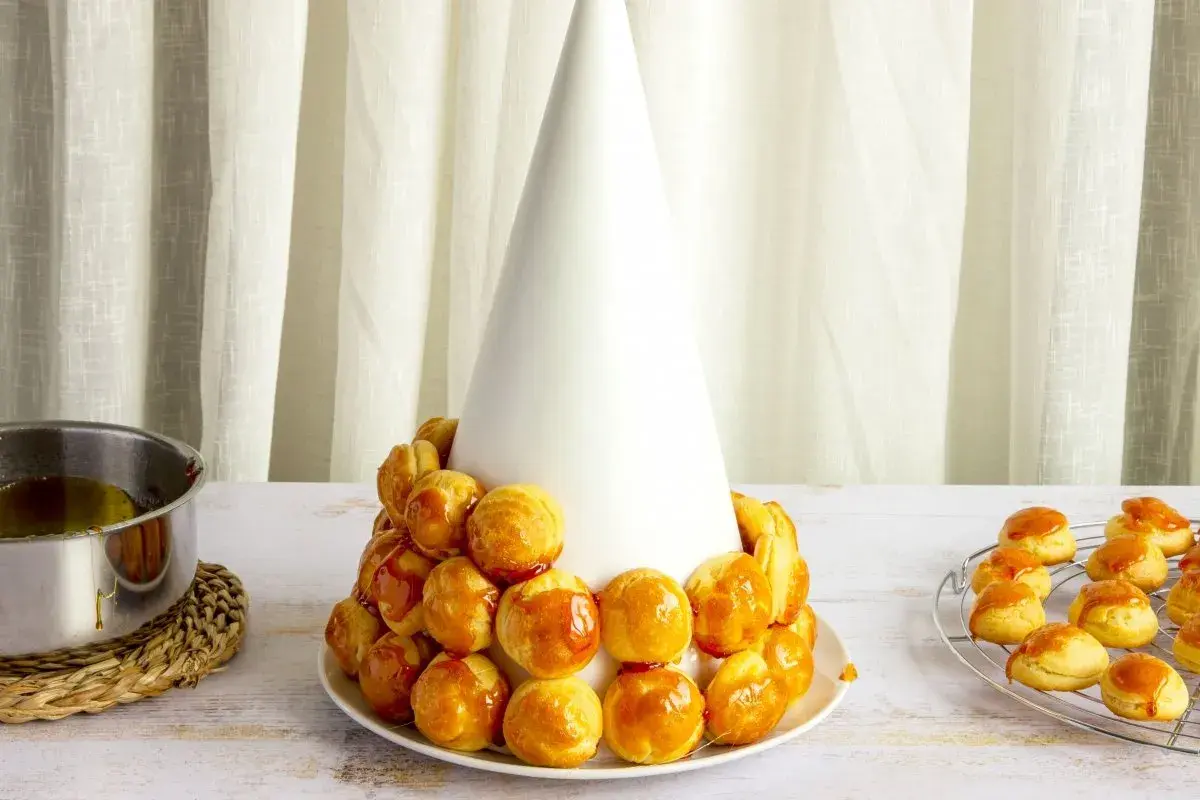 Tarta de profiteroles en proceso, con los pastelitos dorados y brillantes, listos para ser cubiertos de caramelo.