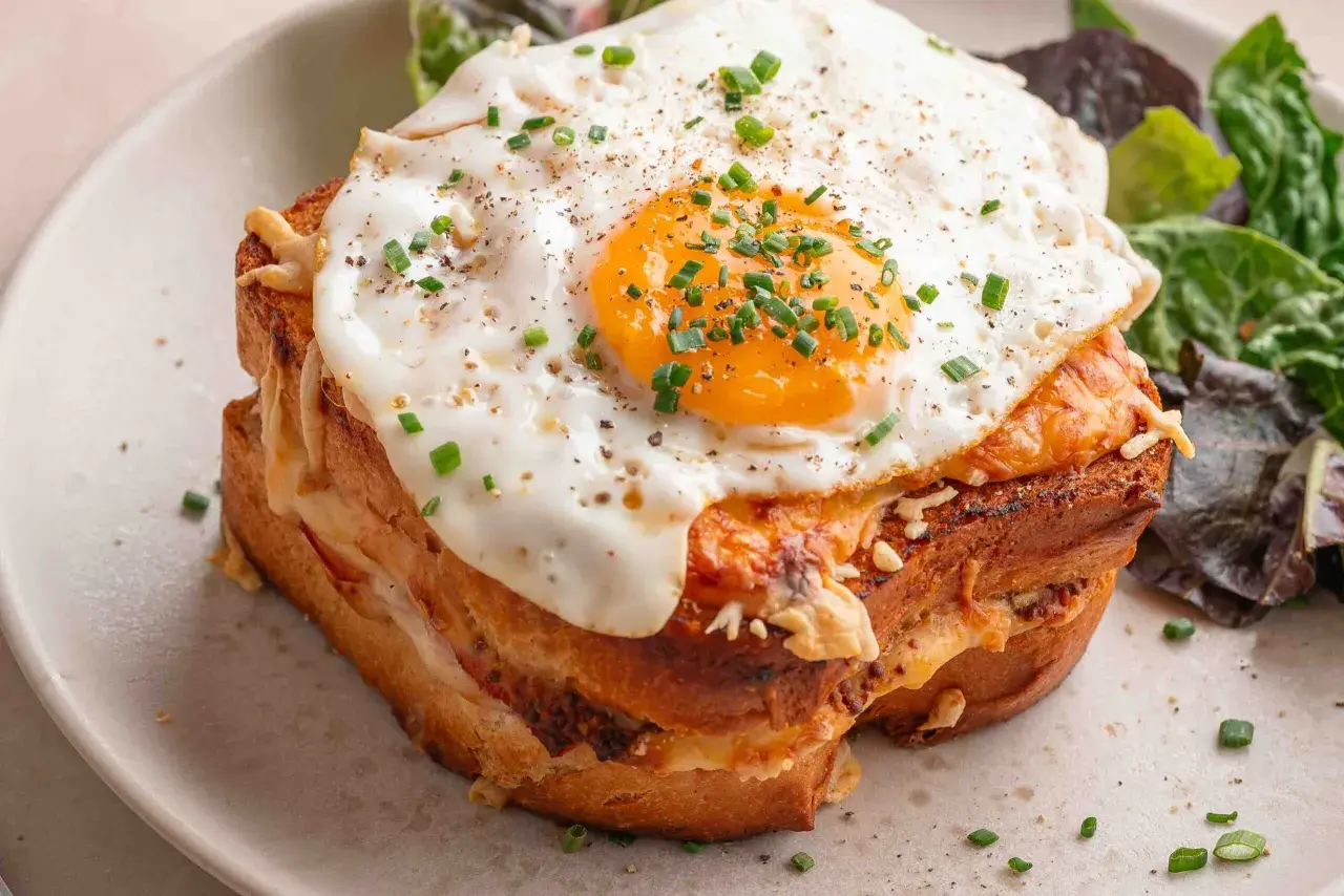 Un délicieux croque madame recette, avec un œuf au plat coulant, du fromage fondant et une salade verte. Un plat gourmand à souhait.