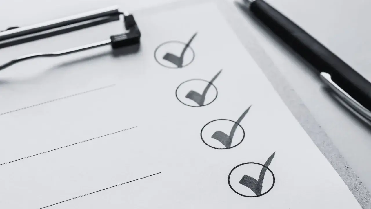 Liste de contrôle pour une visite maison : un stylo noir et un presse-papiers sur une feuille avec des cases cochées.