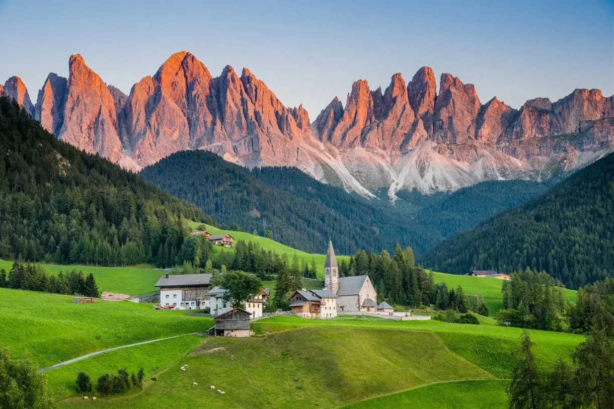 A picturesque village nestled in a valley, with the jagged peaks of the Dolomites catching the golden light, a stark contrast to the gentler slopes of the Alps.