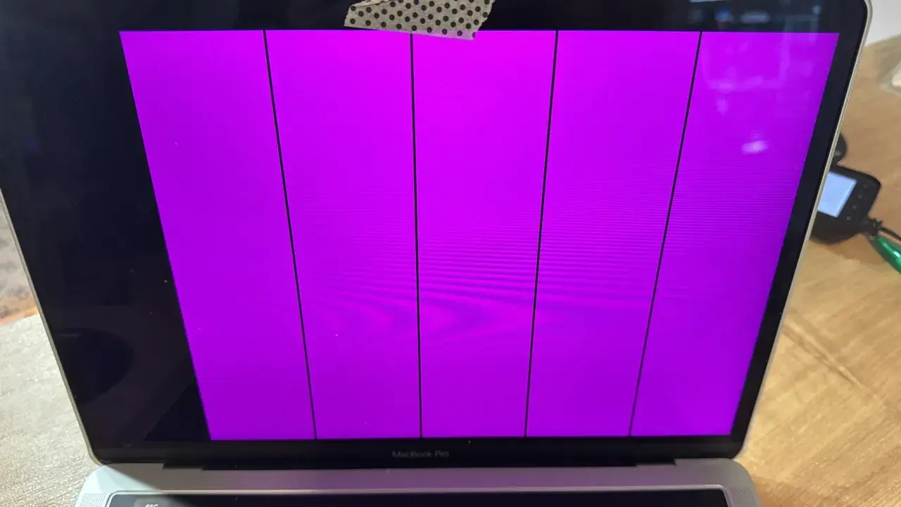 Uszkodzony ekran MacBook Pro wyświetla pionowe fioletowe pasy.
